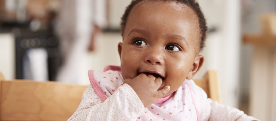 Cute Baby Girl Wearing Bib Sitting In High Chair