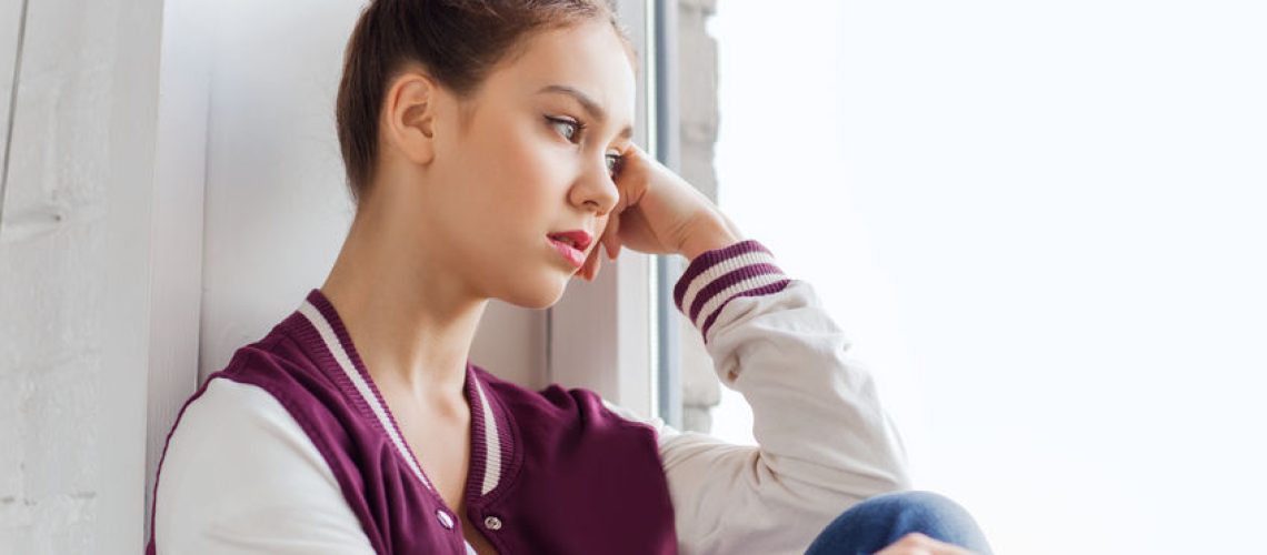 53577929 - people, emotion and teens concept - sad unhappy pretty teenage girl sitting on windowsill