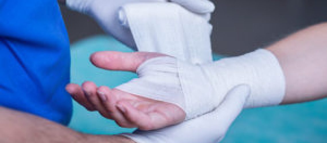 Close-up of male doctor bandaging a hand